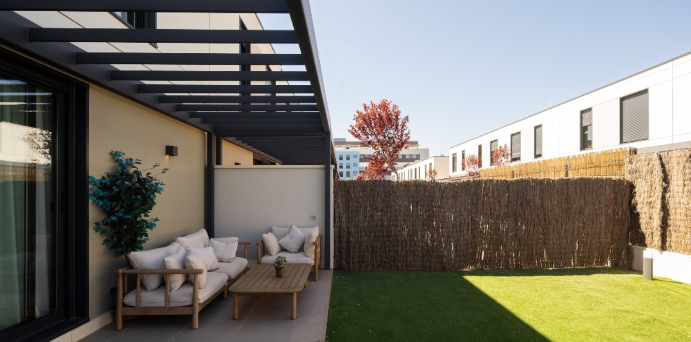Porche y jardín de una vivienda de la promoción industrializada La Maquia de AEDAS Homes en Alcalá de Henares, Madrid