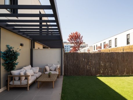 Porche y jardín de una vivienda de la promoción industrializada La Maquia de AEDAS Homes en Alcalá de Henares, Madrid